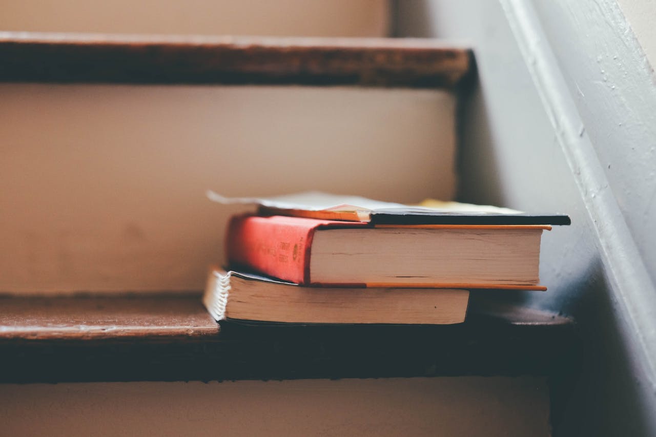 A small pile of books rests on wooden stairs, symbolizing knowledge and education.